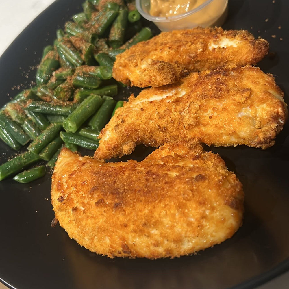 Golden, crispy chicken tenders served with a side of green beans, showcasing a flavorful and protein-packed meal