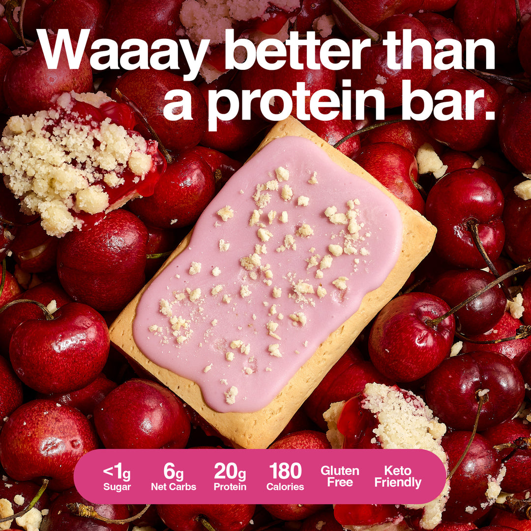 Cherry Crumble protein pastry on fresh cherries with crumble topping. Text: 'Waaay better than a protein bar.' 20g protein, <1g sugar, keto-friendly.