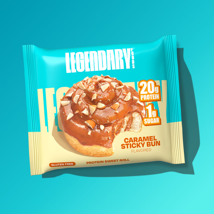 A close-up of a single Legendary Foods Caramel Sticky Bun Protein Sweet Roll pack, showing a caramel-drizzled roll with chopped nuts, 20g protein, 1g sugar.